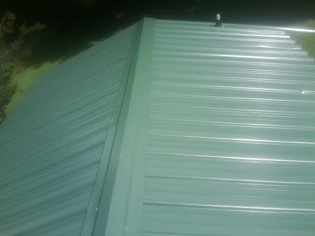 New green metal panels meeting at the ridge of a roof — Flat Roof Repair work by our crew in Williams